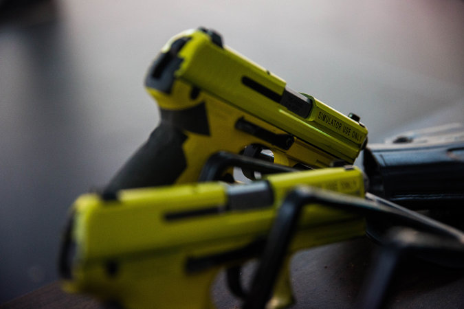 Pistols that fire lasers are used in virtual reality exercises to teach Border Patrol agents how to defuse potentially violent confrontations. Credit Deanna Alejandra Dent for The New York Times