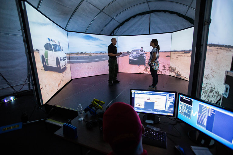 Jason Daniels, an agent with the United States Border Patrol, instructing Fernanda Santos last week during a virtual reality exercise in Tucson. Credit Deanna Alejandra Dent for The New York Times
